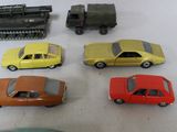 several toy cars are lined up on a table with a train in the background