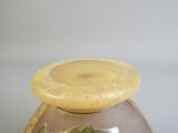 un vase marron avec un couvercle jaune posé sur une table