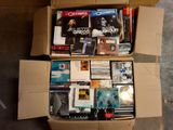 une boîte en carton remplie de DVD et de CD posée par terre