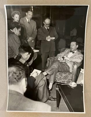 une photo en noir et blanc montrant un groupe d'hommes assis autour d'une table