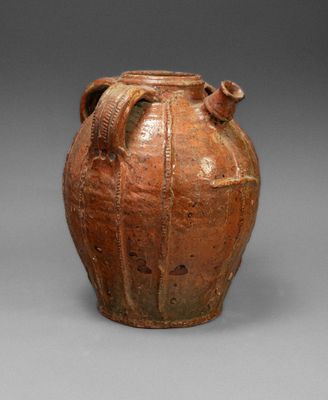 un vieux vase marron muni de deux anses, sur un fond gris