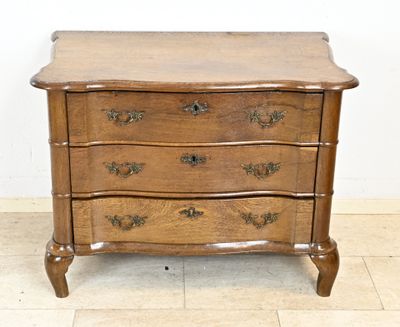 une petite commode en bois posée sur un sol carrelé