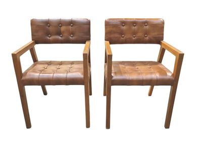 deux chaises en cuir marron assises l'une à côté de l'autre sur une surface blanche