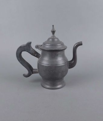 une vieille théière en argent avec une anse, sur fond gris