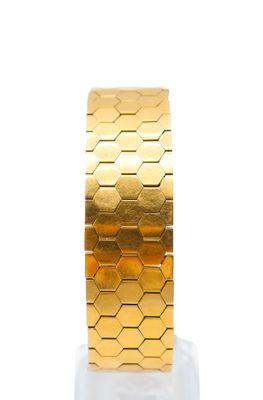 gold plated bracelet on a marble base with a white background