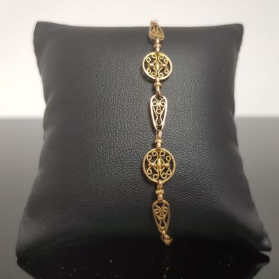 un gros plan d'un bracelet en or posé sur un coussin noir