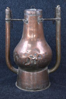 a large copper pot sitting on a stand on a blue surface