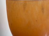a large orange bowl sitting on a table next to a window