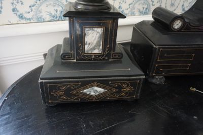 une petite horloge posée sur une table, à côté d'une boîte noire