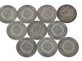 six types différents de pièces d'argent sur une surface blanche
