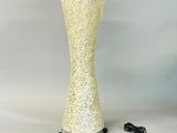 a tall yellow vase with a black cord on it