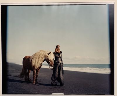 une femme debout à côté d'un cheval sur la plage