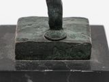 statue of a hand holding a coin on top of a stone block