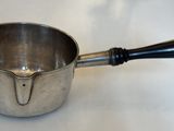 une casserole en argent avec une poignée noire posée sur une table blanche