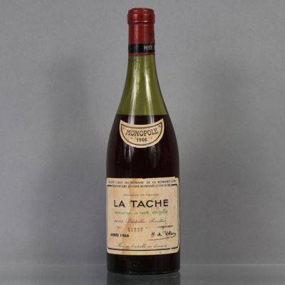 une bouteille de vin « La Tache » posée sur une table, sur fond gris