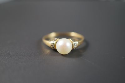 gros plan d'une bague en or avec une perle et des diamants