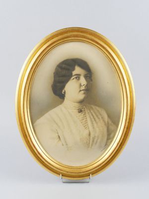 une vieille photo d'une femme en robe blanche, dans un cadre doré