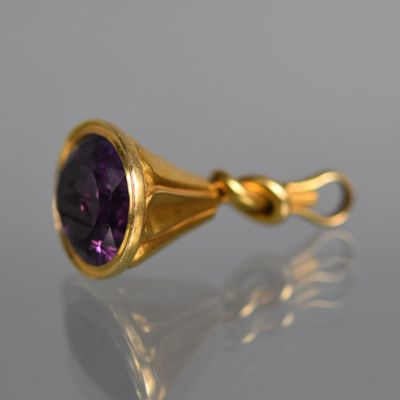 une image représentant un pendentif en or et en améthorate orné d'une pierre violette