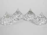 four clear glass pieces of candy sitting on top of a white surface