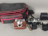 un appareil photo, un étui pour appareil photo, un appareil photo et d'autres objets posés sur une table