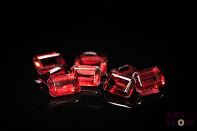 quatre perles cubiques en verre rouge sur un fond noir