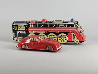 a red toy car next to a train on a white surface