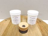 deux pots de crème posés sur une table en bois, à côté d'un pot de crème