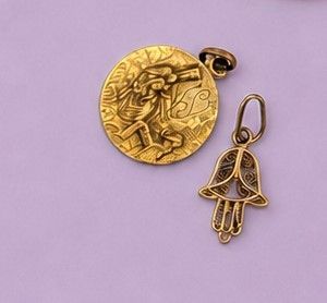 une breloque en forme de main de Hamsa plaquée or et une pièce d'or sur fond violet