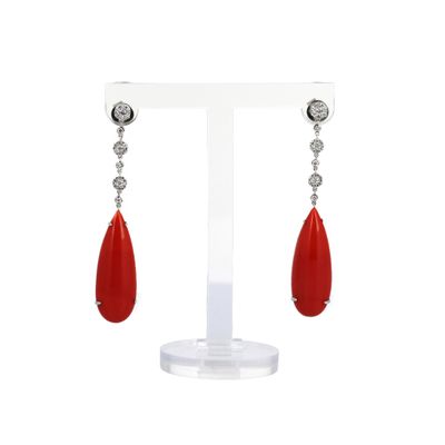 une paire de boucles d'oreilles rouges et blanches posées sur un présentoir blanc