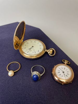 trois bagues, une montre, une bague, une bague et une bague posées sur un tissu bleu