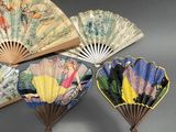 four chinese folding paper fans with designs on them on a table