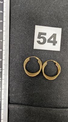 Deux paires de boucles d'oreilles créoles en or sont présentées à côté d'une règle.