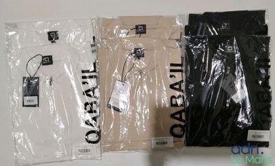 trois t-shirts dans des sacs en plastique, posés sur une table