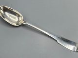 silver plated spoon with a spoon handle on a gray surface