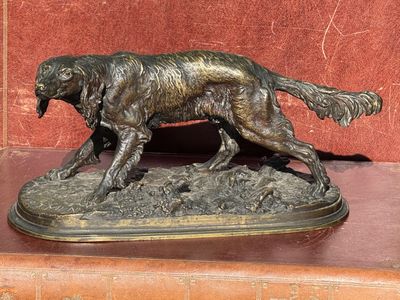 statue en bronze représentant un chien sur un socle, avec un fond rouge