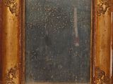 an old picture of a mirror with a gold frame on a wall