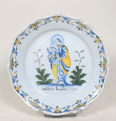 une assiette bleue et jaune sur laquelle est représentée une femme tenant un bébé dans ses bras