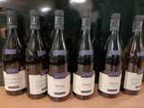 six bouteilles de vin sont alignées sur une table