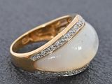 a close up of a ring with a white stone surrounded by diamonds