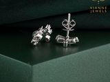 pair of silver earrings on a green box with a black background