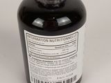 a bottle of black liquid sitting on top of a white table