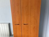 two wooden cupboards in a room with a radiator and a heater
