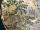 a plate with a painting on it sitting on a table