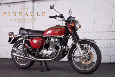 a red motorcycle parked in front of a white brick wall
