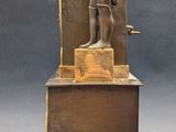 a bronze statue of a man reading a book on a stand