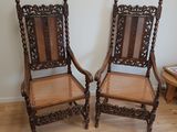 une paire de chaises anciennes en bois sculpté avec des assises en osier, dans un salon