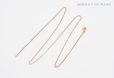 a pair of gold necklaces on a white background