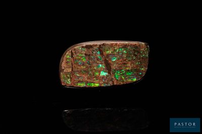 a close up of a ring with green and red oplite in it