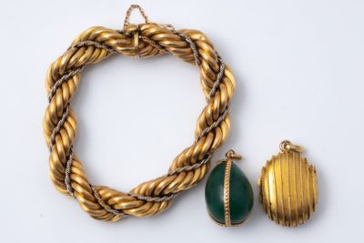 two pieces of gold and green jewelry on a white surface