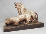une statue représentant un lion et une lionne, posée sur un socle en bois